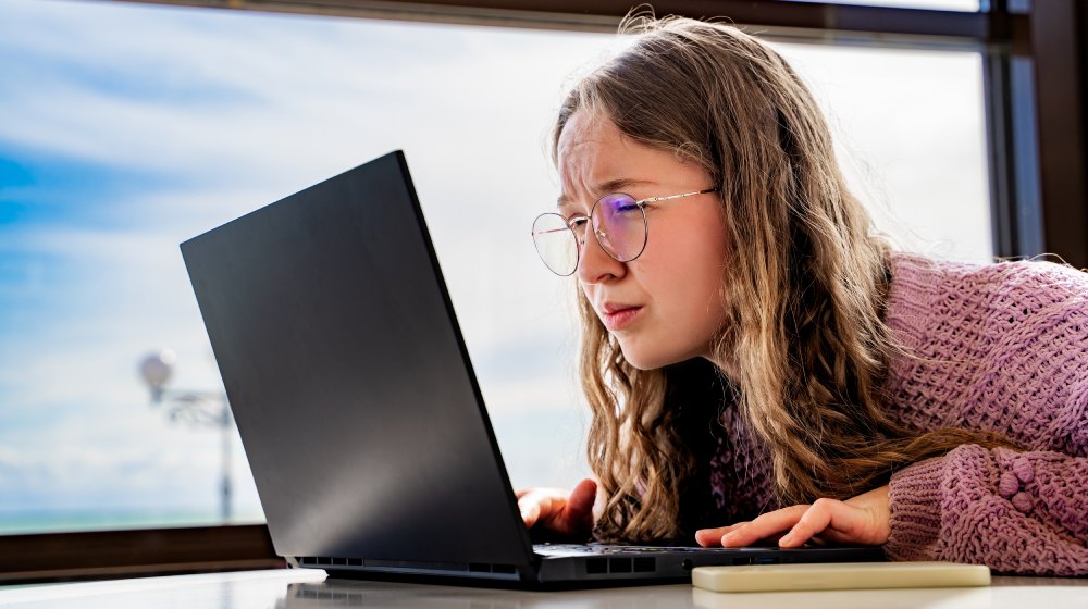 dziewczyna w okularach wpatrująca się w ekran laptopa