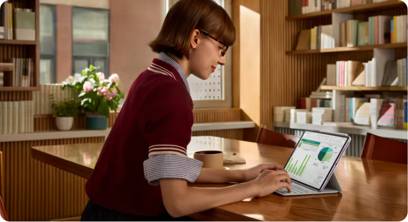 kobieta z tabletem, która jest w trakcie nauki przy biurku