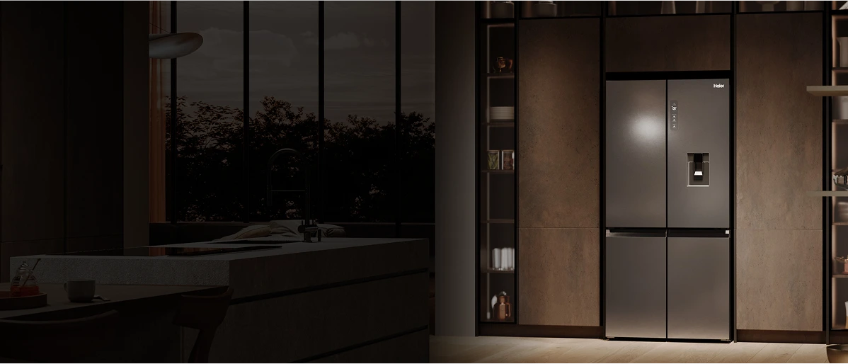 Nowoczesna kuchnia z brązowo-szarym wystrojem, minimalistycznym blatem, stalową lodówką i dużymi oknami z widokiem na drzewa w zmierzchu.