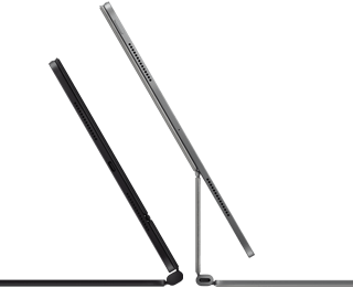 Dwa widoczne z boku smukłe iPady Pro podłączone do klawiatur Magic Keyboard, jednej w kolorze gwiezdnej czerni, nachylonej i półotwartej, z głośnikami i portem USB‑C, i drugiej w kolorze srebrnym, otwartej i nachylonej tak, że widać konstrukcję wspornika, głośników i mikrofonu