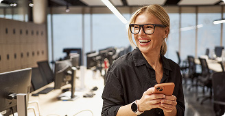 Dwóch współpracowników uśmiecha się i patrzy na laptopa, siedząc razem przy biurku.