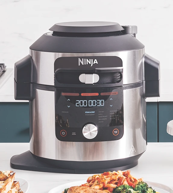Multicooker Ninja Foodi Max OL750EU stojący obok białego tortu na blacie kuchennym