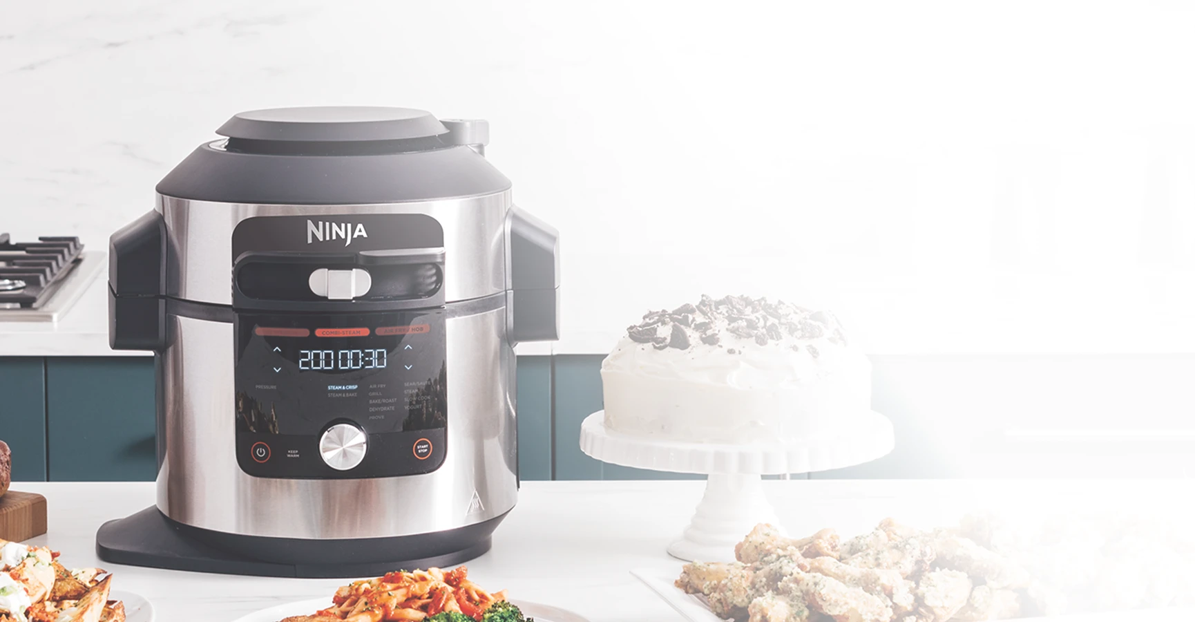 Multicooker Ninja Foodi Max OL750EU stojący obok białego tortu na blacie kuchennym