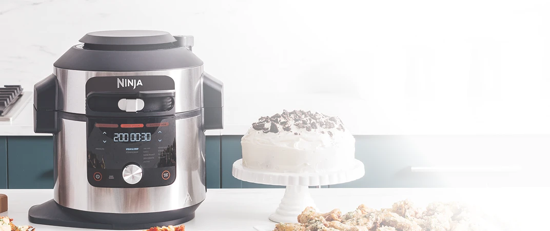 Multicooker Ninja Foodi Max OL750EU stojący obok białego tortu na blacie kuchennym