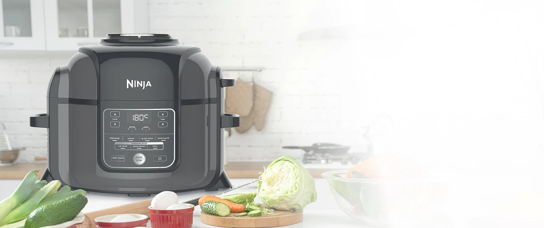 Ninja Foodi OP300EU stojący obok na blacie kuchennym w otoczeniu warzyw