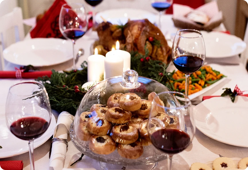 Zbliżenie na elegancko zastawiony stół świąteczny z białymi talerzami, potrawami świątecznymi, ciasteczkami i lampkami wina