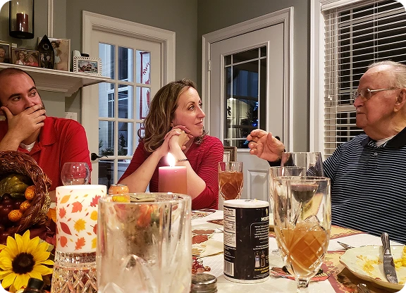 Członkowie rodziny siedzą przy zastawionym stole świątecznym i rozmawiają