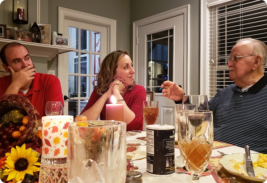 Członkowie rodziny siedzą przy zastawionym stole świątecznym i rozmawiają