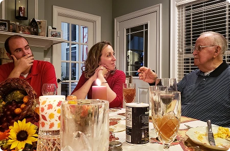 Członkowie rodziny siedzą przy zastawionym stole świątecznym i rozmawiają