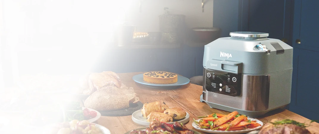 Ninja Speedi ON400EU stoi na stole w otoczeniu rozmaitych potraw świątecznych, pieczywa i ciast