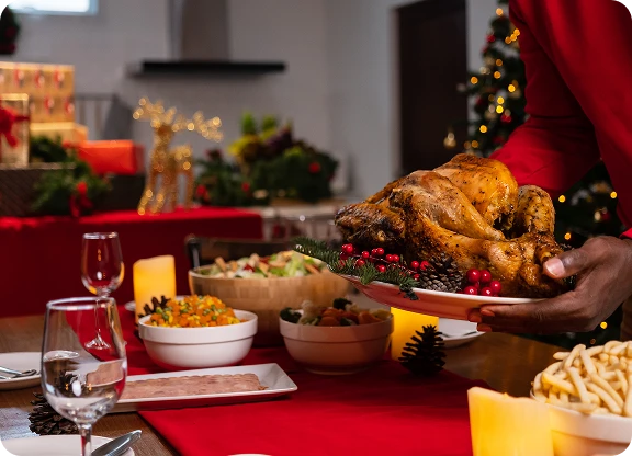 Mężczyzna kładzie upieczonego kurczaka na świątecznym stole pełnym innych potraw