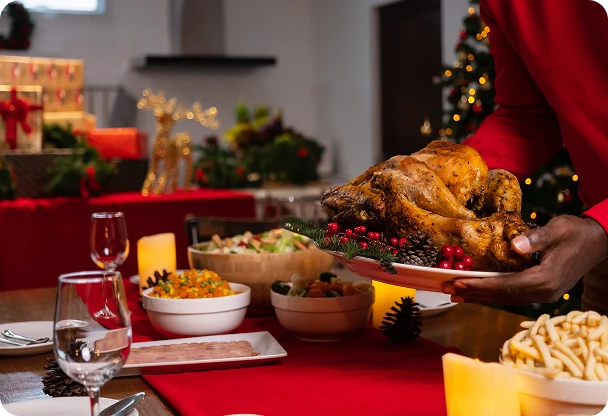 Mężczyzna kładzie upieczonego kurczaka na świątecznym stole pełnym innych potraw