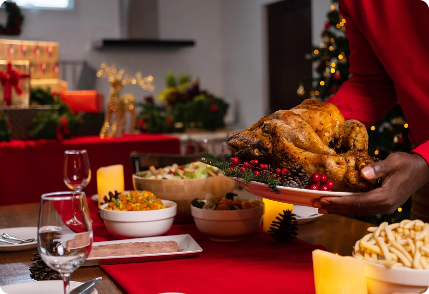 Mężczyzna kładzie upieczonego kurczaka na świątecznym stole pełnym innych potraw