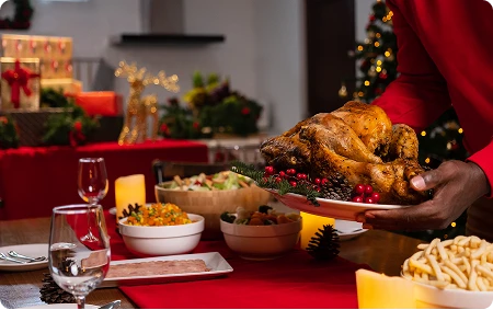 Mężczyzna kładzie upieczonego kurczaka na świątecznym stole pełnym innych potraw