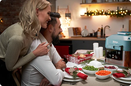 Mężczyzna i kobieta przy świątecznym stole patrzą na Ninja Speedi ON400EU i się uśmiechają