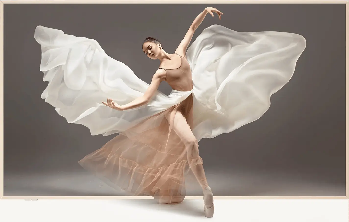 Elegancka baletnica w białej sukni z rozwiewającym się materiałem na ekranie telewizora w smukłej ramce