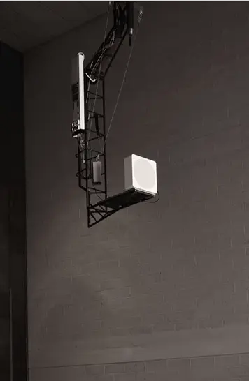 Urządzenie pomiarowe akustyki zawieszone na wysięgniku w ciemnym pokoju laboratoryjnym z szarą ścianą