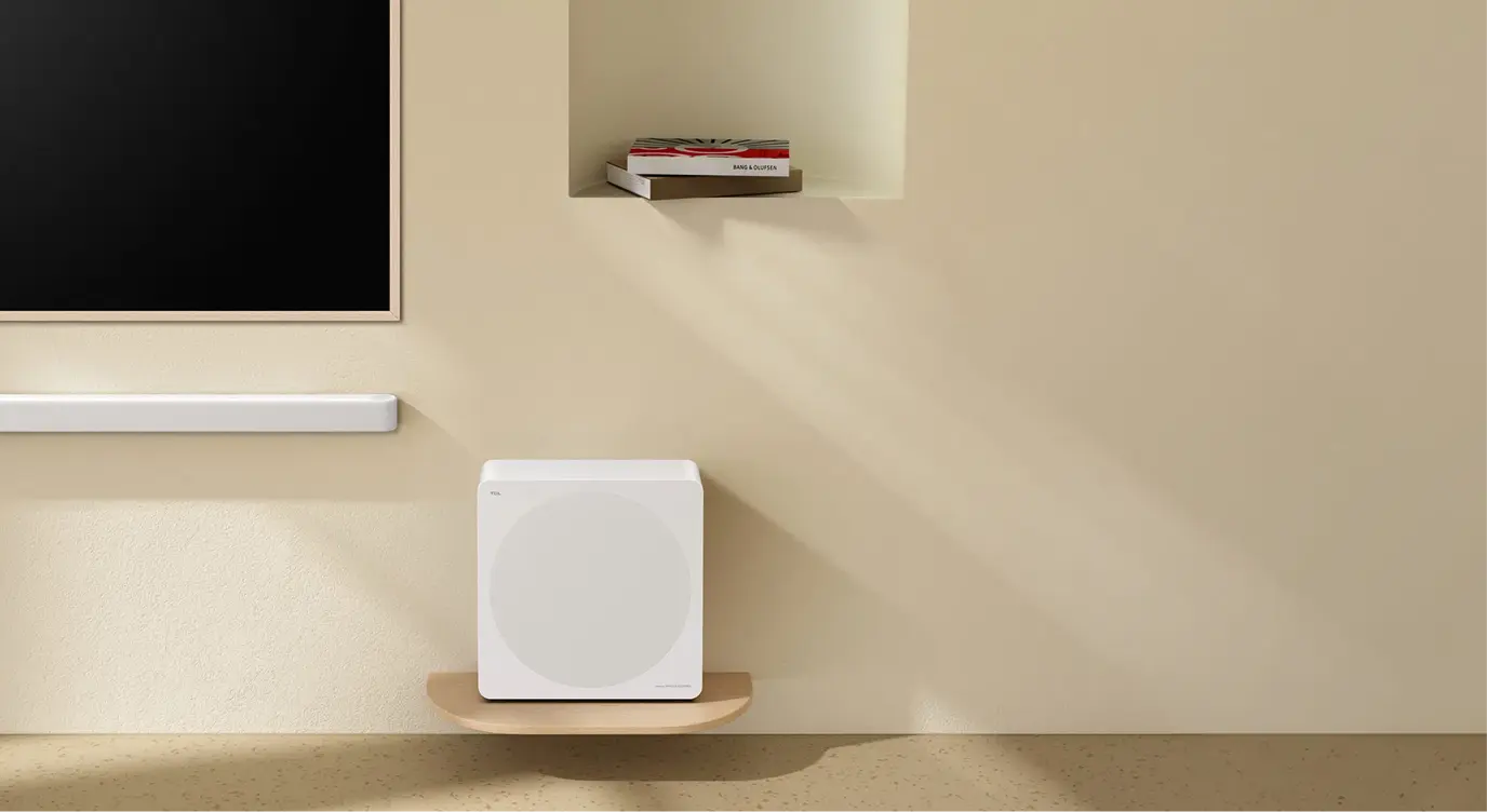 Biały soundbar Bang & Olufsen i subwoofer na drewnianych półkach w beżowym minimalistycznym wnętrzu