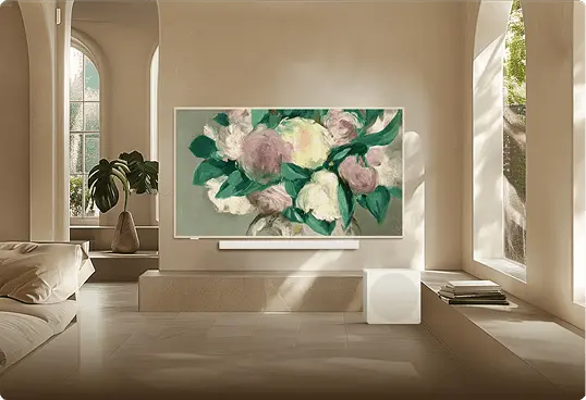 Telewizor TCL z kwiatowym obrazem na uchwycie ściennym w beżowym salonie z łukowymi oknami i rattanowym fotelem