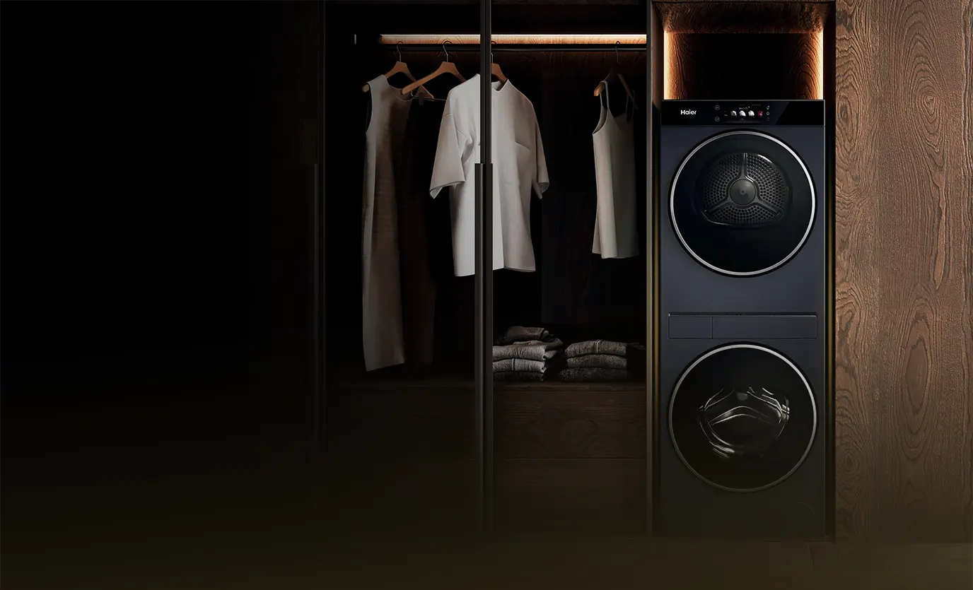 Pralka i suszarka Haier Couture Care Collection 11 w zabudowie obok szafy z ubraniami na wieszakach.