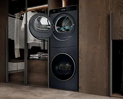 Czarna pralka i suszarka ustawione pionowo w drewnianej wnęce, z otwartymi drzwiczkami.