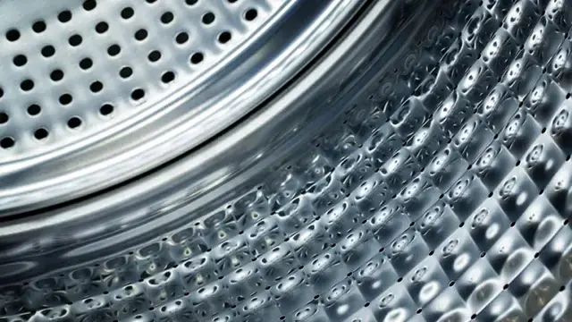 Wnętrze bębna pralki ze stali nierdzewnej z widocznymi otworami wentylacyjnymi.