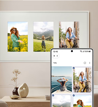 Smartfon z różnymi zdjęciami kobiet na ekranie, w tle na ścianie w jasnym pokoju wisi telewizor z tymi samymi obrazami.