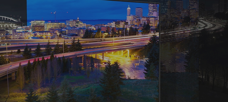 Oświetlone droga kilkupasmowa prowadząca do dużego miasta tuż przed nadejściem zmroku.