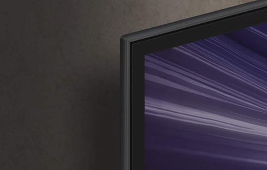 Róg telewizora, stojącego w ciemnym pomieszczeniu, na którego ekranie widać fioletowy obraz.