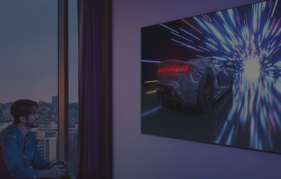 Mężczyzna grający na dużym telewizorze wiszącym na ścianie w grę wyścigową.