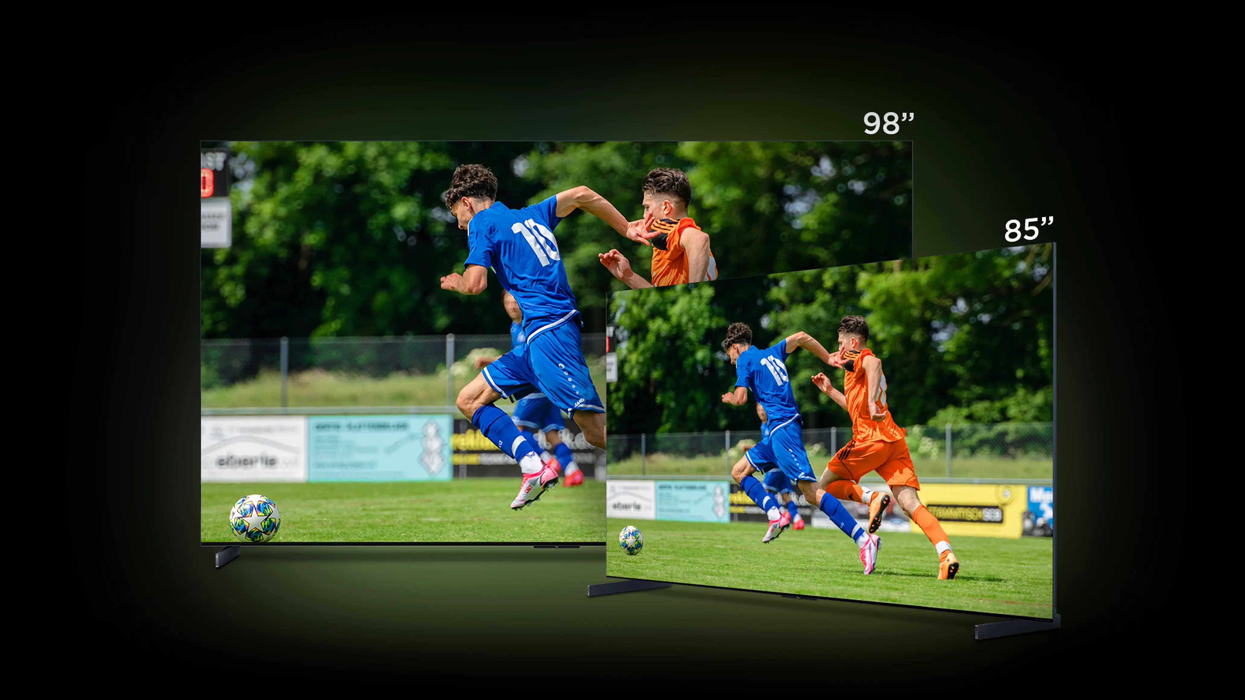Porównanie dwóch dużych telewizorów 98 i 85 cali z obrazem meczu piłki nożnej na boisku.