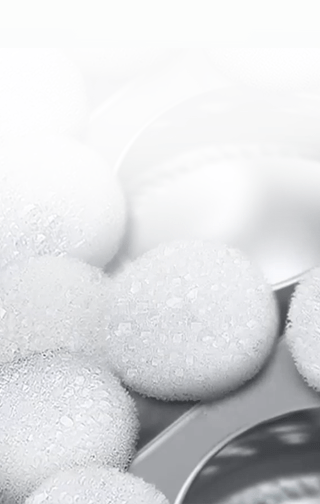 Białe drobinki piany, znajdujące się na ściankach bębna pralki.