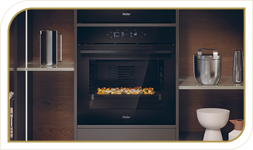 Piekarnik Haier w zabudowie z uchylonymi drzwiami, w środku pieczone warzywa. Po bokach półki z akcesoriami kuchennymi.