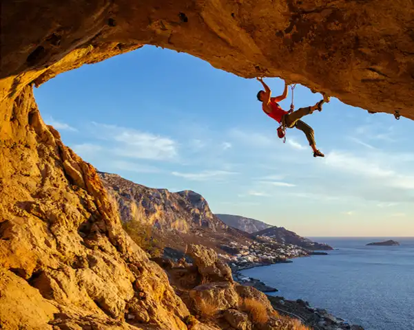 Mężczyzna wspinający się po skale nad morzem podczas aktywności outdoorowej