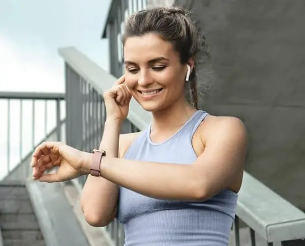 Kobieta w słuchawkach sprawdza smartwatch Hama podczas treningu