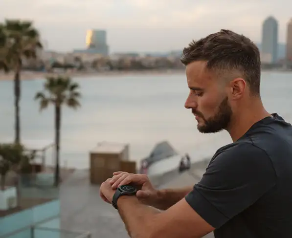 Mężczyzna sprawdza smartwatch Hama na nadgarstku na tle miasta