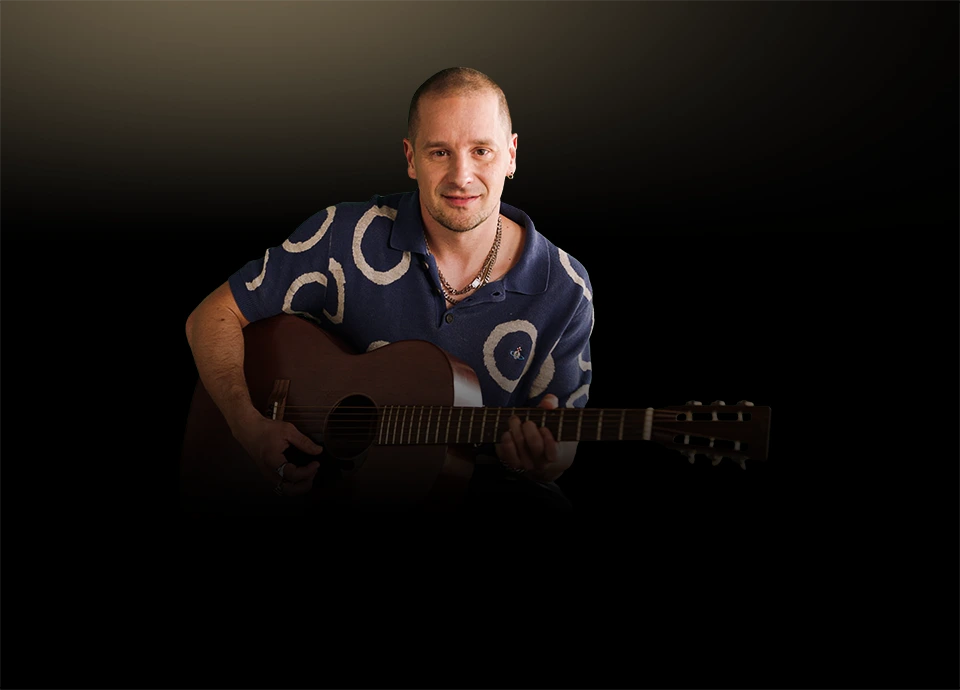 Mężczyzna siedzący z gitarą akustyczną