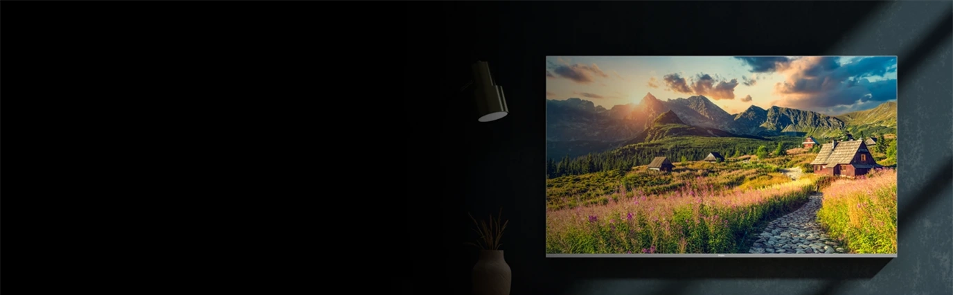 Telewizor ścienny Haier w ciemnym wnętrzu wyświetlający górski krajobraz
