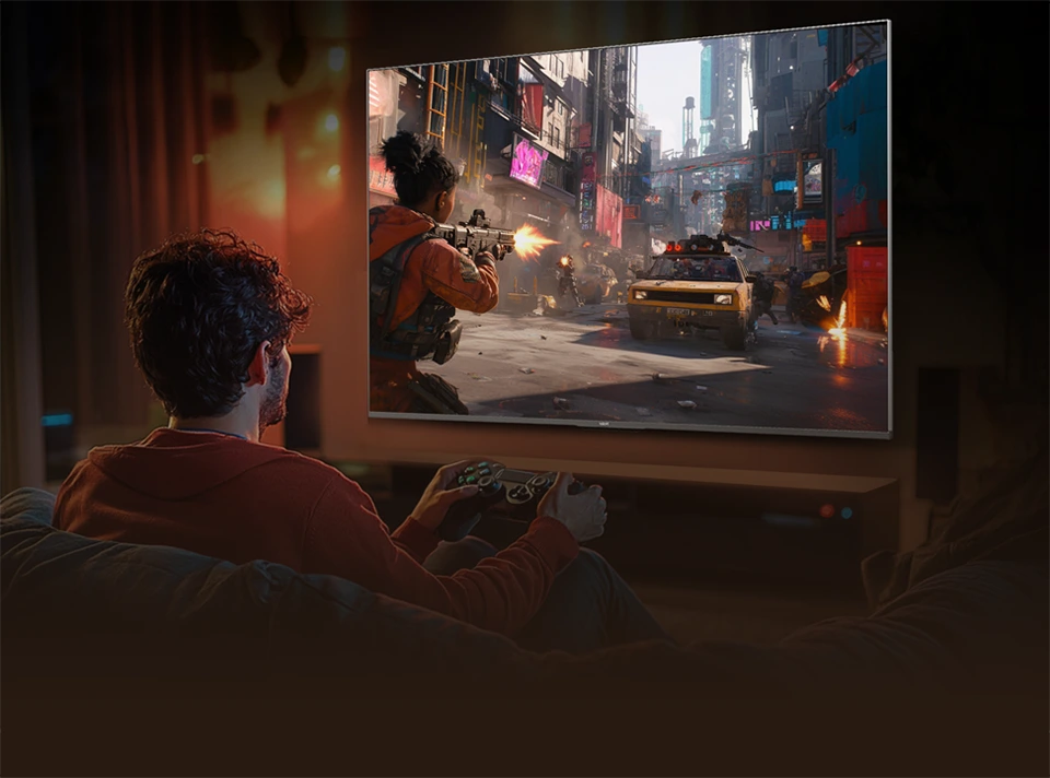 Mężczyzna grający na konsoli przed telewizorem Haier wyświetlającym dynamiczną scenę gry akcji