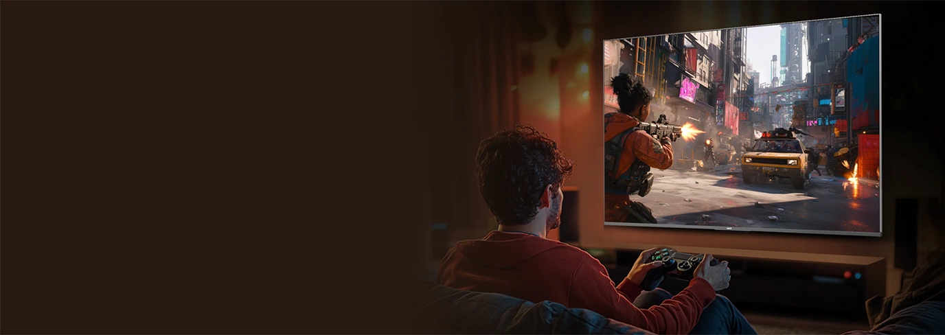 Mężczyzna grający na konsoli przed telewizorem Haier wyświetlającym dynamiczną scenę gry akcji