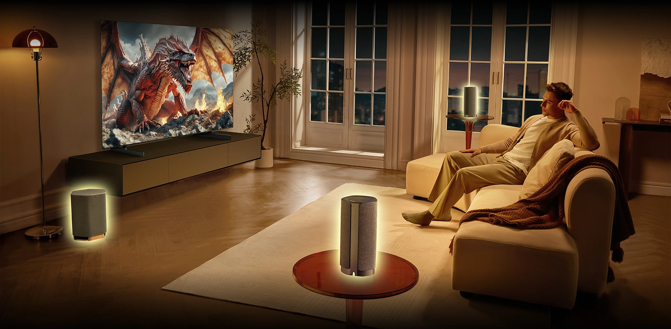 Mężczyzna ogląda telewizję w salonie otoczony głośnikami Z100 tworzącymi system kina domowego