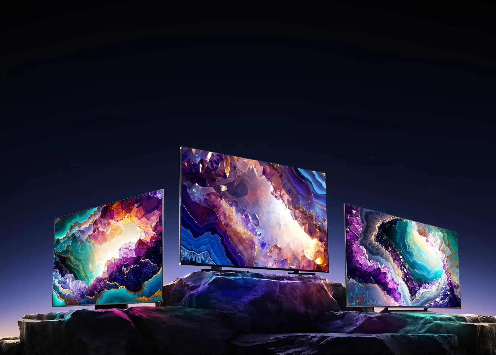 Trzy telewizory Hisense RGB MiniLED na tle kolorowych minerałów w ciemnym krajobrazie skalnym
