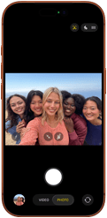 Przód iPhone’a 17 Pro w kolorze kosmicznego pomarańczu. Na ekranie kadr z aparatu przedniego Center Stage z wycentrowanym grupowym selfie pięciu osób
