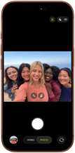 Przód iPhone’a 17 Pro w kolorze kosmicznego pomarańczu. Na ekranie kadr z aparatu przedniego Center Stage z wycentrowanym grupowym selfie pięciu osób