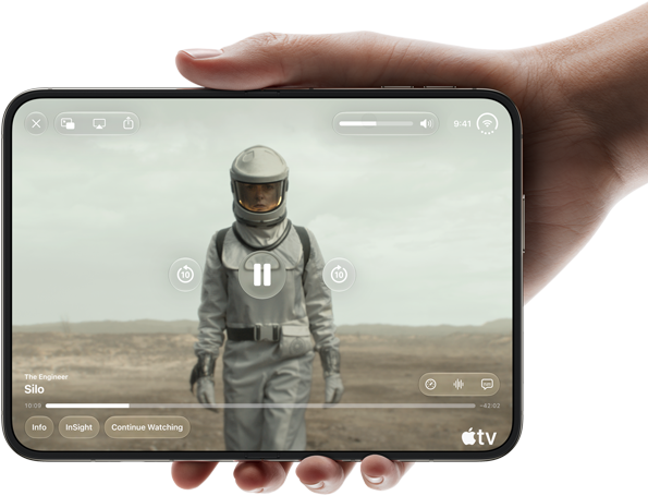 Całkowicie rozłożony iPhone Duo trzymany w jednej dłoni w pozycji poziomej, na wyświetlaczu wewnętrznym widać serial „Silos” w apce Apple TV