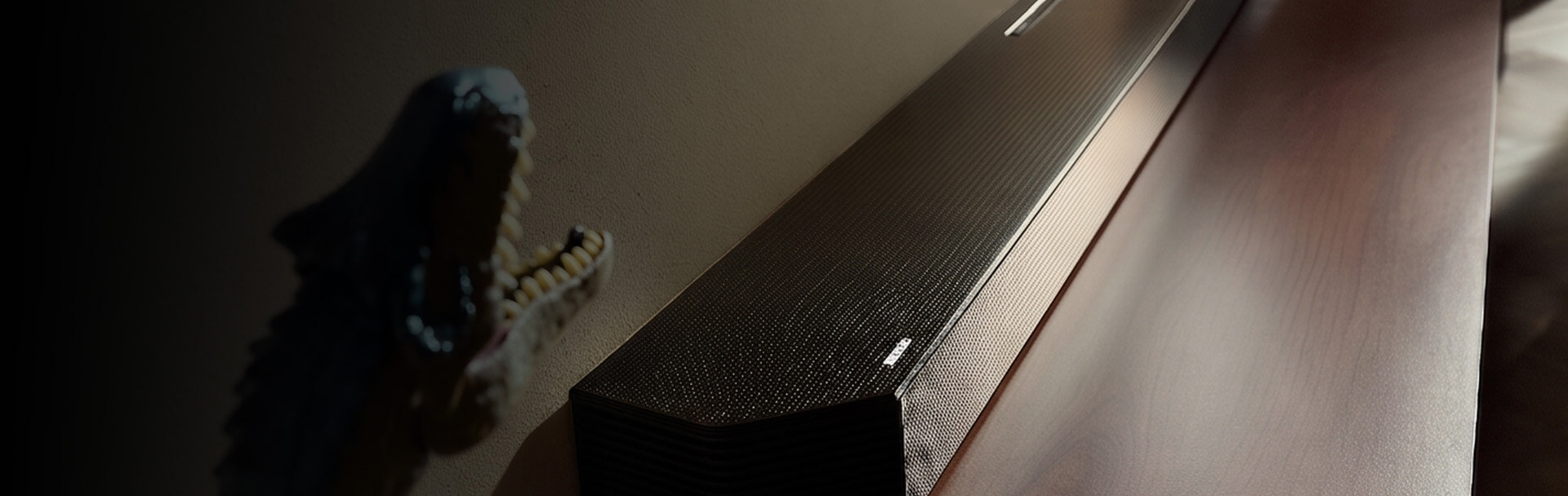 Czarny soundbar znajduje si&eogon; na p&oacute;lce w towarzystwie kolorowych wazon&oacute;w i lamp.