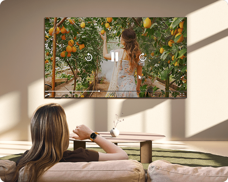 Kobieta sterująca telewizorem Samsung ruchem ręką z Galaxy Watch